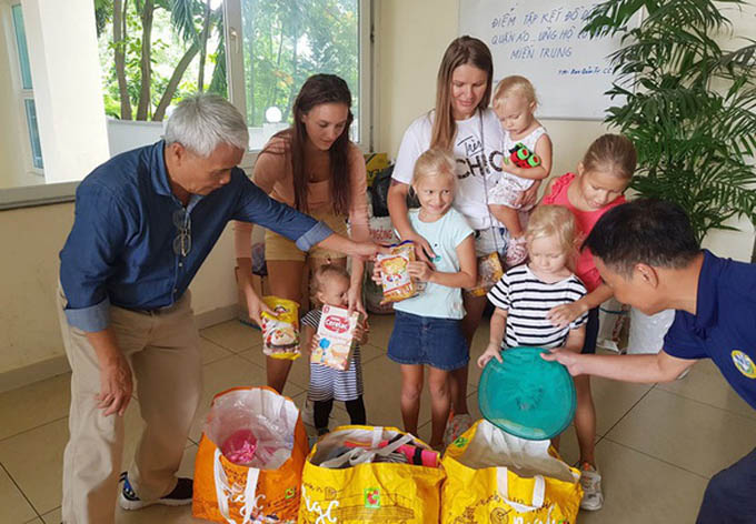 Hai nữ du khách Nga mắc kẹt tại Việt Nam bế con đi mua đồ cứu trợ dân vùng lũ